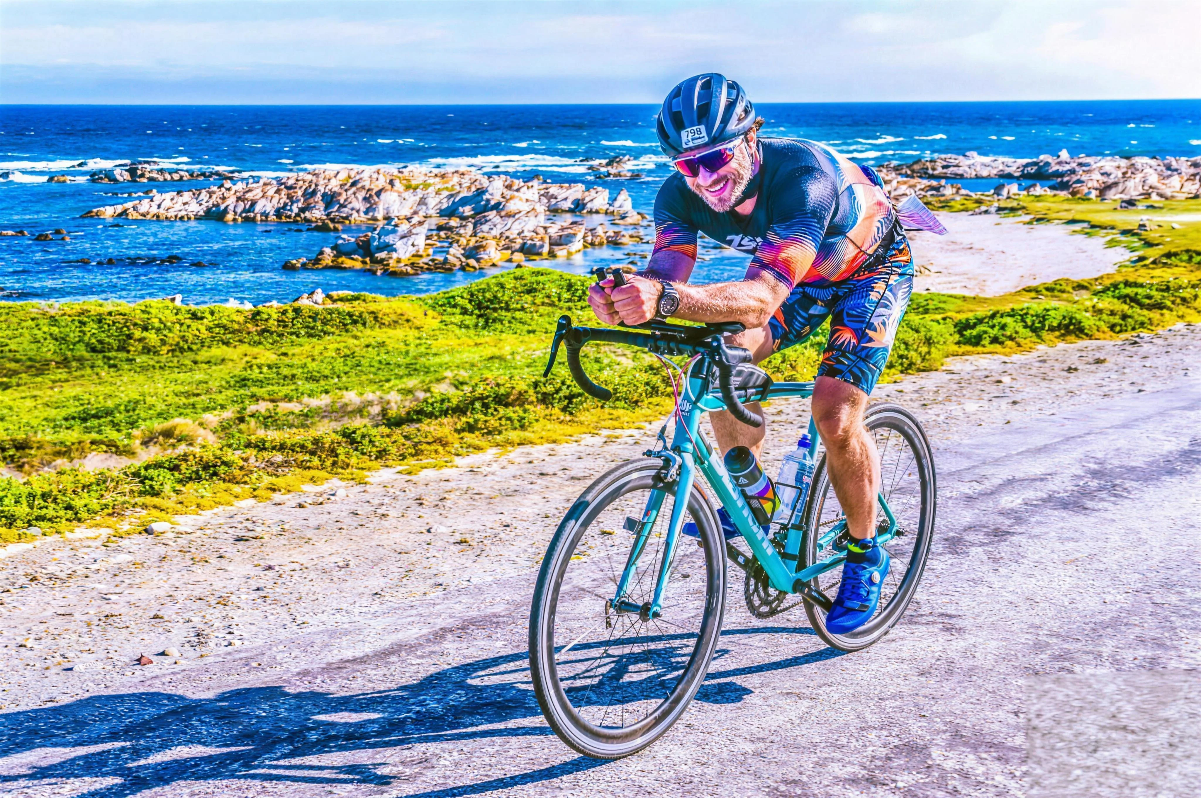 Mateusz Romanowski na rowerze podczas triathlonu, na tle oceanu